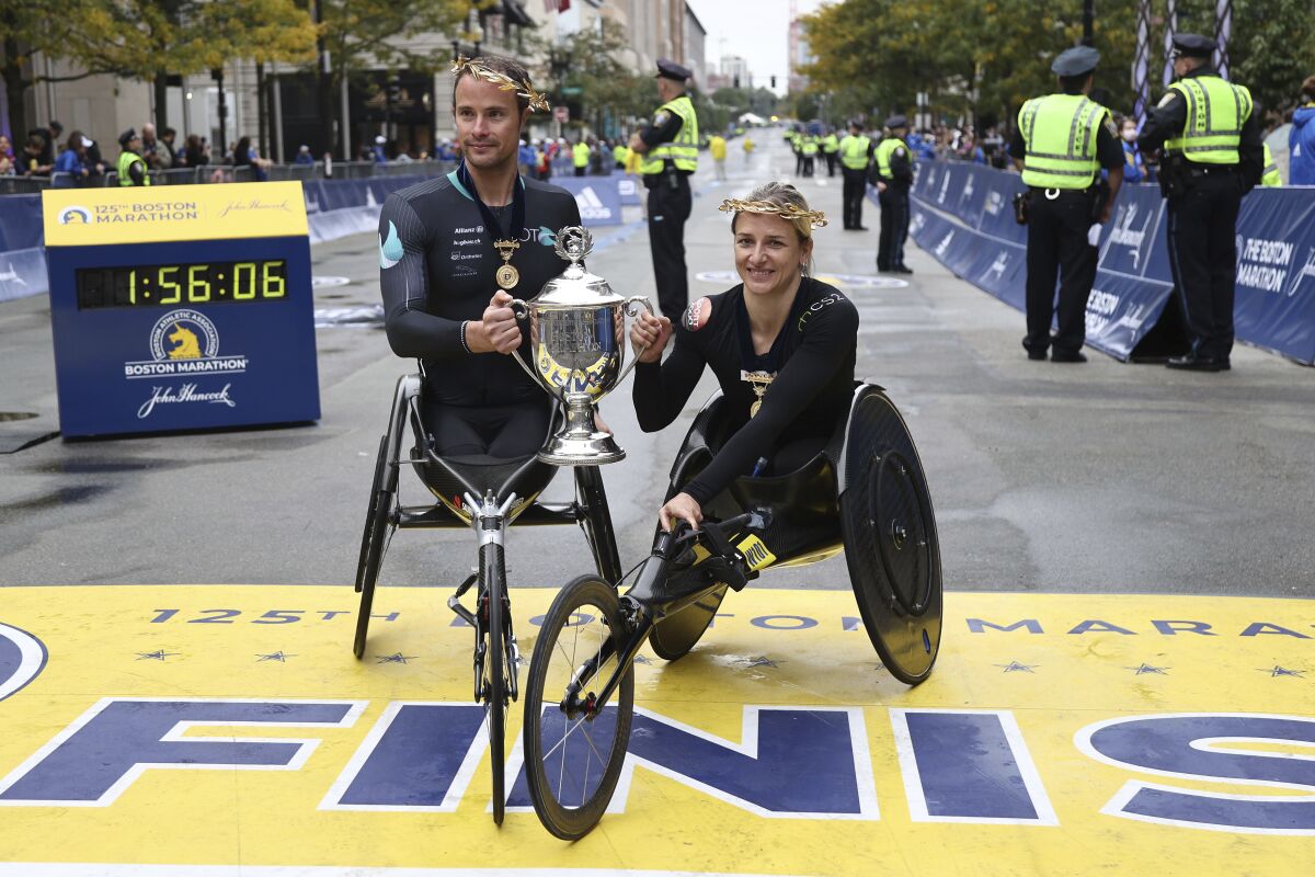 Marcel Hug, left, and Manuela Schar, both of Switzerland, pose after winning the wheelchair divisions of the 125th Boston Marathon on Monday, Oct. 11, 2021, in Boston. (AP Photo/Winslow Townson)