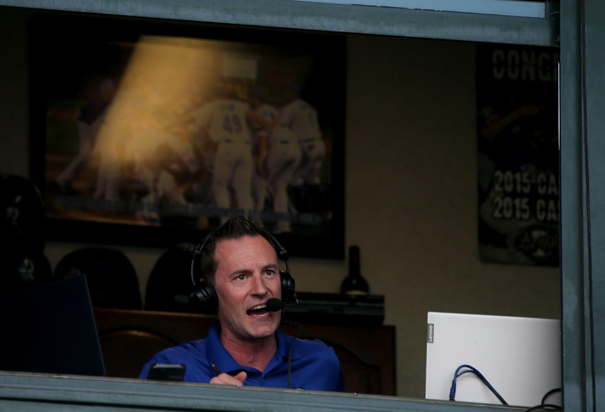 A man wearing a headset sits in the broadcast booth