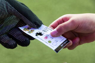 A dark gloved hand and another hand holding a ticket