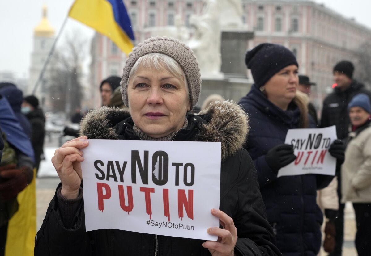 A woman holds a sign saying "Say no to Putin."