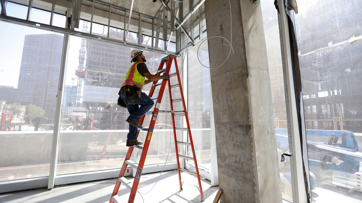 Some state lawmakers have been wanting to deal with the affordable-housing issue before grappling with a cap-and-trade extension. Above, electrician Jaime Sanchez works at a construction site in downtown Los Angeles in 2016.