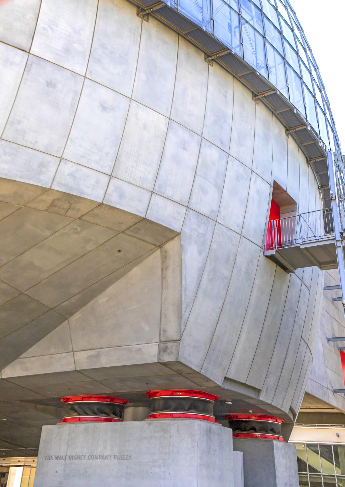 Base isolators, red and black circular forms at the base of the new Academy Museum's sphere, are left exposed.