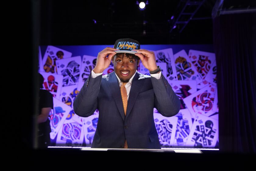 Boston College offensive lineman Zion Johnson puts on a hat after being chosen by the Los Angeles Chargers with the 17th pick of the NFL football draft Thursday, April 28, 2022, in Las Vegas. (AP Photo/John Locher)