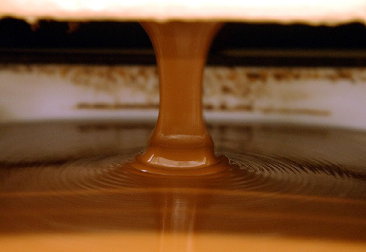 Milk chocolate pours into molds to make chocolate bars at the Guittard Chocolate Co. in Burlingame, Calif.