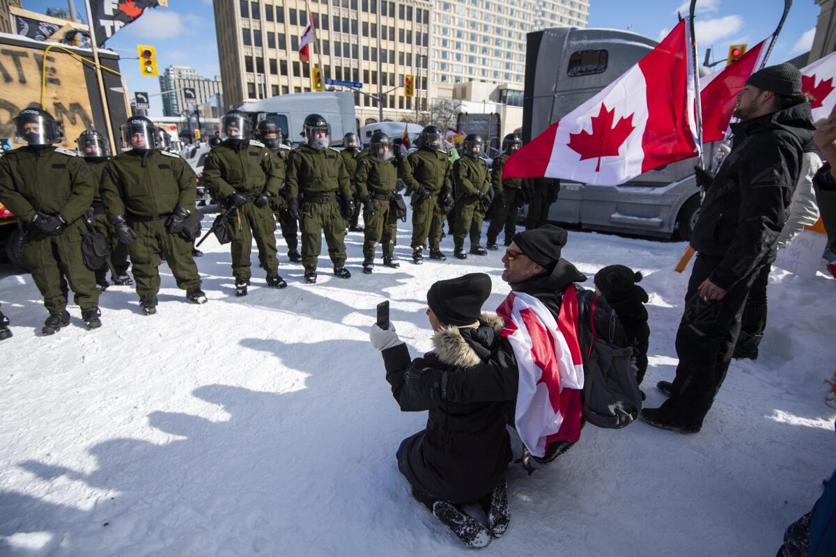Protesters kneel in front of officers in Ottawa on Friday.
