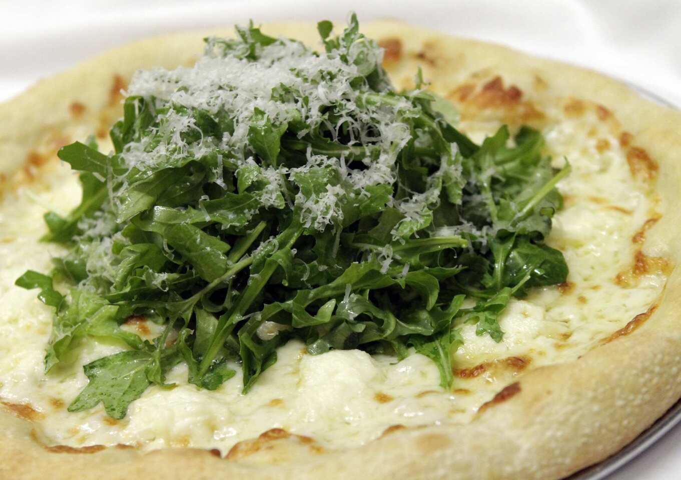 The bianca-verde pizza is topped with preserved lemon, garlic, ricotta, arugula and grated Reggiano cheese.