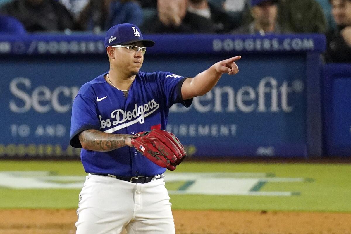 Dodgers starting pitcher Julio Urías gestures after shortstop Miguel Rojas throws out a runner at first base.