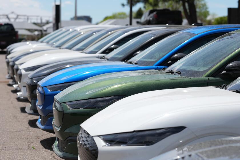 Unsold 2026 Mustang Mach E electric utility vehicles sit in a long line outside a Ford agency Sunday, April 12, 2026, in Centennial, Colo. (AP Photo/David Zalubowski)