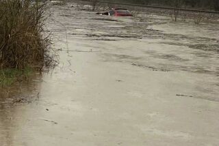 In this photo provided by Layton Hoyer, a red SUV is seen submerged in floodwater on Old Ritchey Road in Granby, Mo., early Friday, March 24, 2023. Hoyer rescued an elderly woman from the car. (Layton Hoyer via AP)
