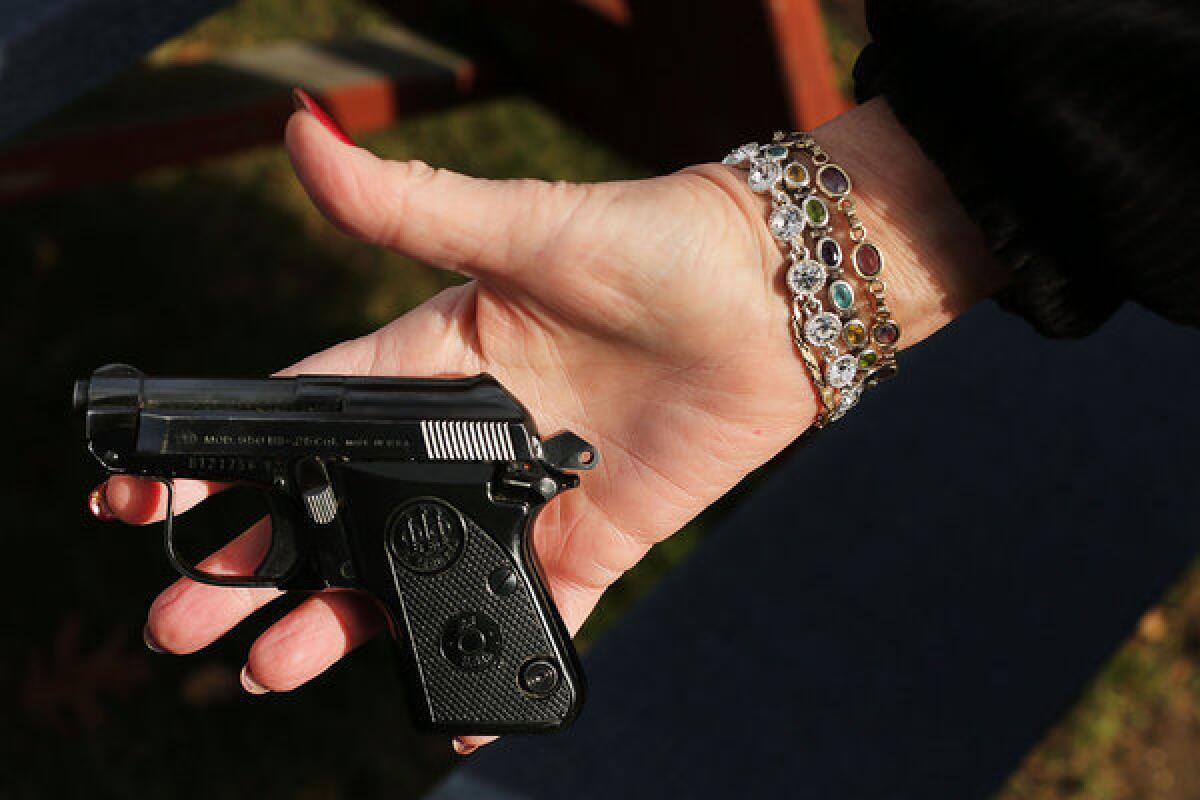 A woman holds a Beretta pistol at a gun buyback event at the Bridgeport Police Department's Community Services Division in Connecticut.