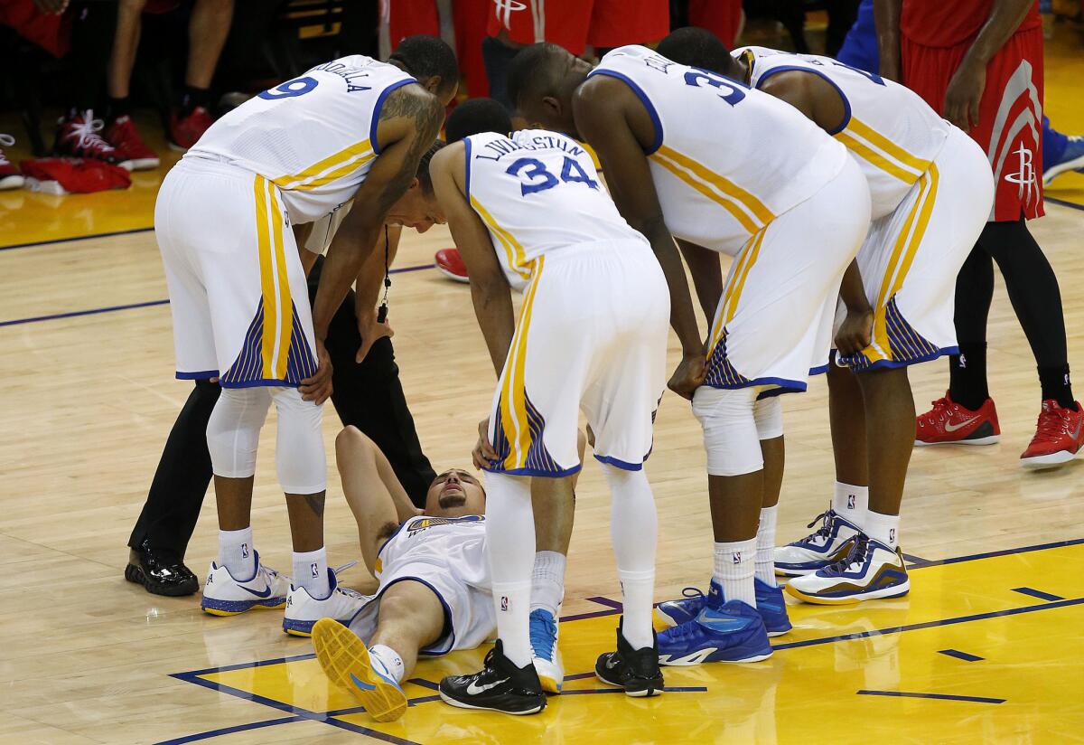 Klay Thompson is surrounded by his Golden State Warriors teammates after being hit in the head by a knee during a Western Conference finals game against the Houston Rockets.