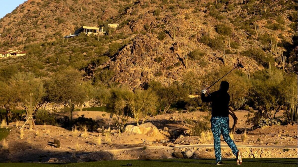 A golfer hits off a tee at the newly redesigned course with Camelback Mountain as a backdrop at the Phoenician in Scottsdale, Ariz.