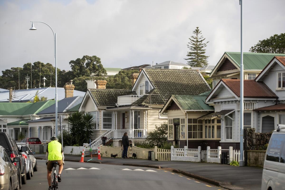 A man cycles past houses in Devonport, suburban Auckland, New Zealand, on June 30, 2022. A Thursday, Aug. 11, 2022, report shows that New Zealand house prices fell for the first annual decline in more than a decade as rising interest rates finally halted a boom which only accelerated after the coronavirus pandemic hit. (Michael Craig/New Zealand Herald via AP)