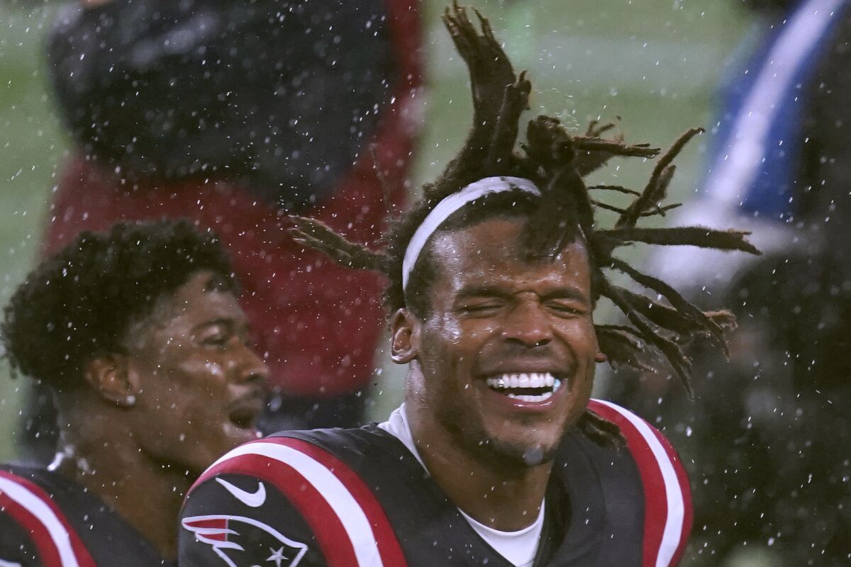 New England Patriots quarterback Cam Newton celebrates in the driving rain after defeating the Baltimore Ravens in an NFL football game, Sunday, Nov. 15, 2020, in Foxborough, Mass. (AP Photo/Elise Amendola)