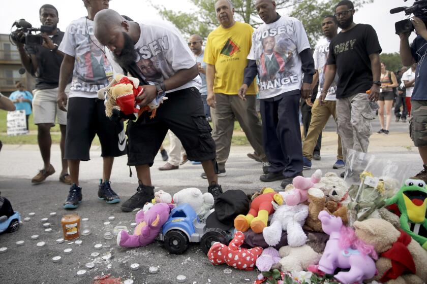 Michael Brown Sr. drops off stuffed animals at a memorial to his son, Michael Brown, before taking part in a parade in his son's honor Saturday in Ferguson, Mo.