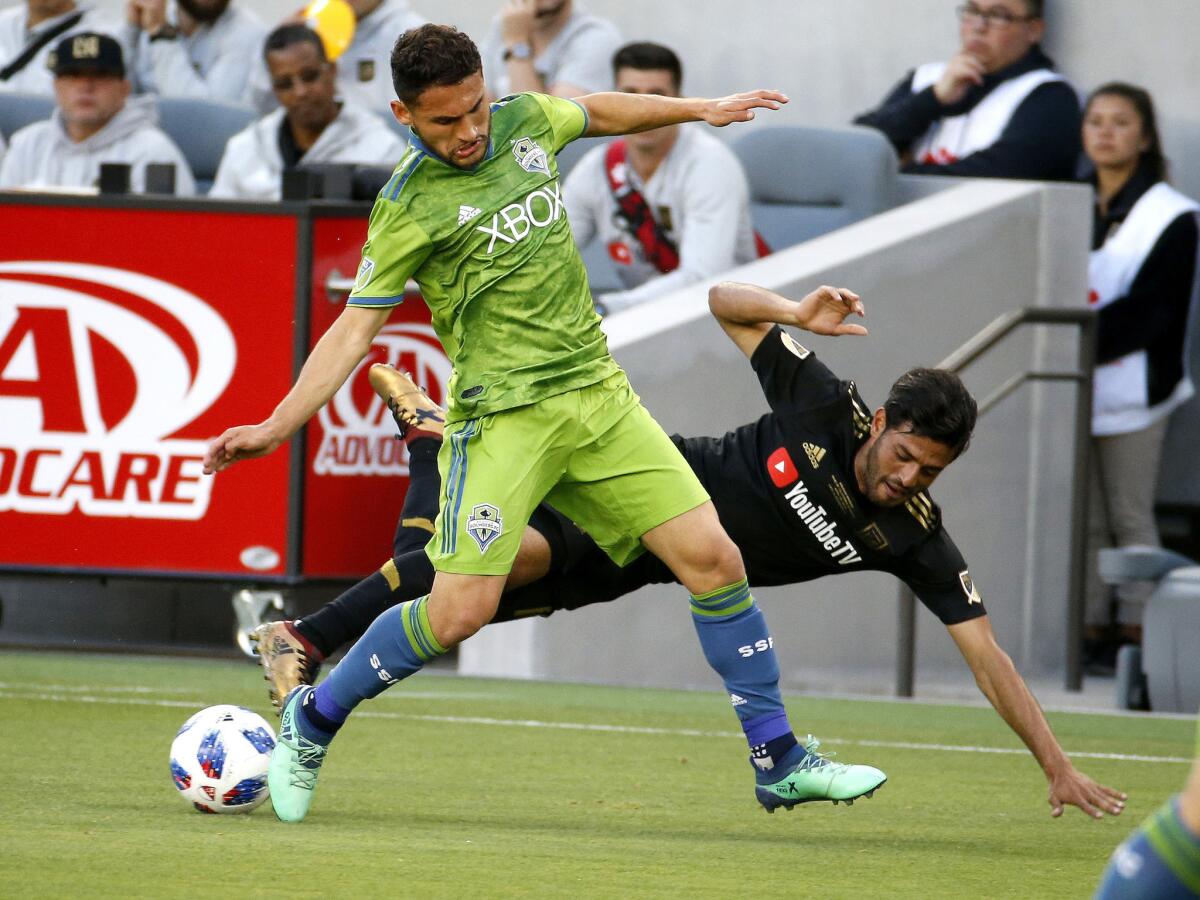 Seattle Sounders midfielder Cristian Roldan (7) vies for the ball with Los Angeles FC forward Carlos Vela (10) of Mexico, in the first half of an MLS soccer game at Banc of California Stadium in Los Angeles, Sunday, April 29, 2018.