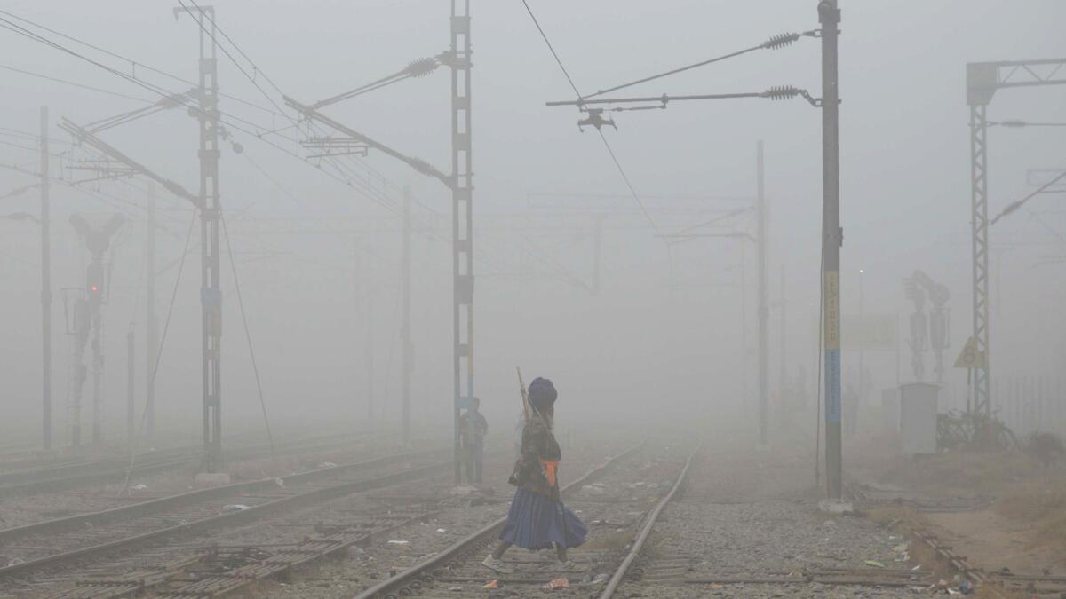 A Nihang, or traditional Sikh army member, crosses railway tracks amid dense smog near Amritsar railway station.