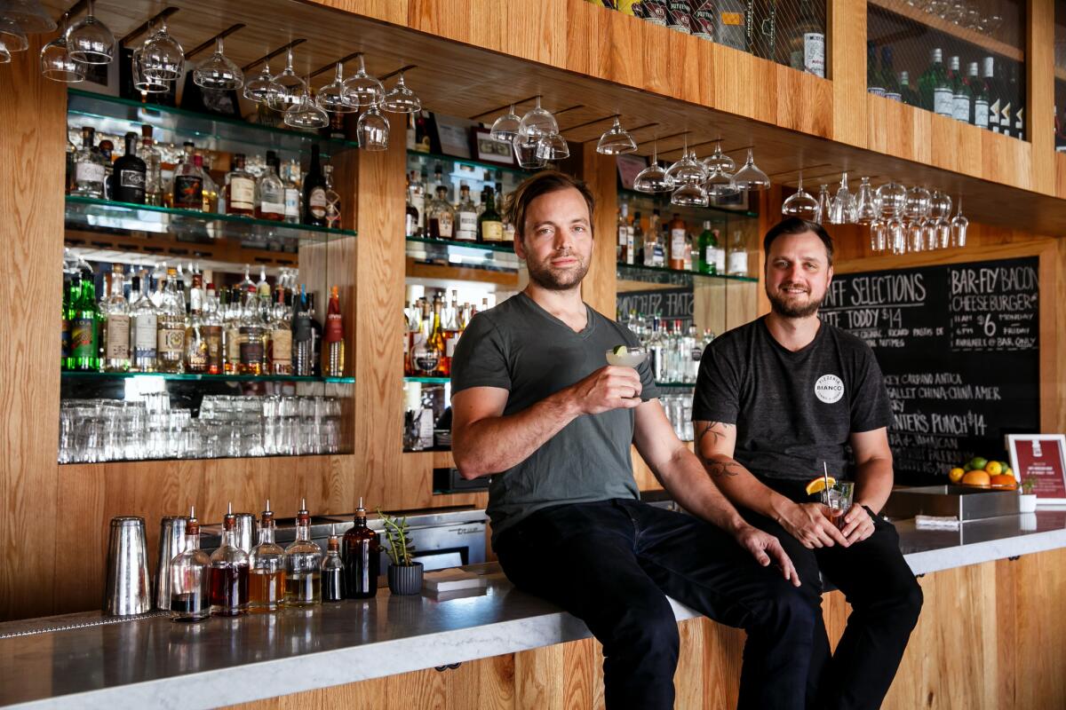 Salt's Cure chefs Chris Phelps, left, and Zak Walters perch atop the bar at their restaurant's new location on Highland.