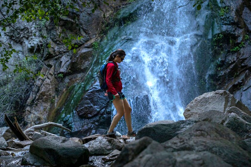 A hiker walks carefully on rocks at Sturtevant Falls in Angeles National Forest.