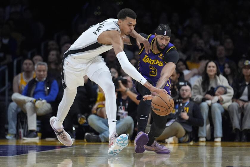 San Antonio Spurs center Victor Wembanyama (1) reaches for the ball next to Los Angeles Lakers forward Anthony Davis (3) during the first half of an NBA basketball game Friday, Feb. 23, 2024, in Los Angeles. (AP Photo/Marcio Jose Sanchez)