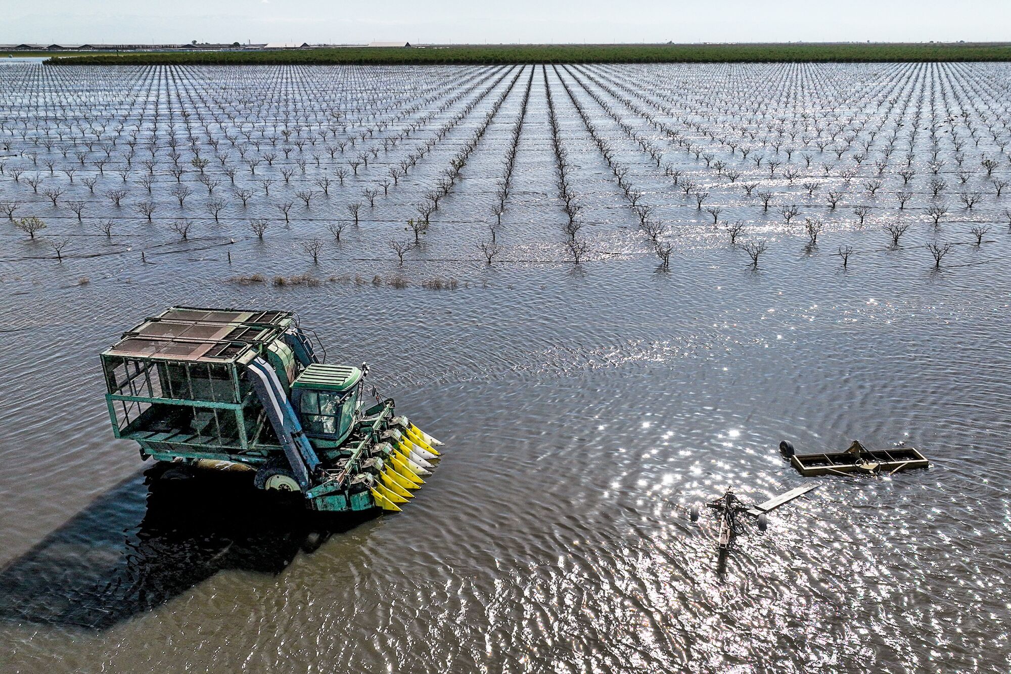 An aerial frame of farm machinery flooded in a vineyard