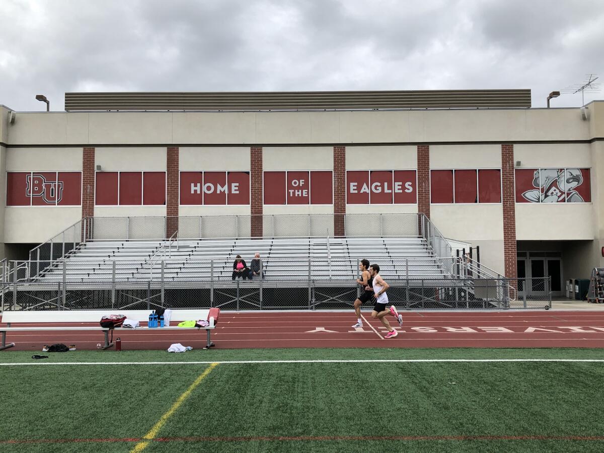 Gabe Plendcio, in black, races assistant coach Ryan Thompson during a time trial in the mile March 14, 2020, at Biola University.