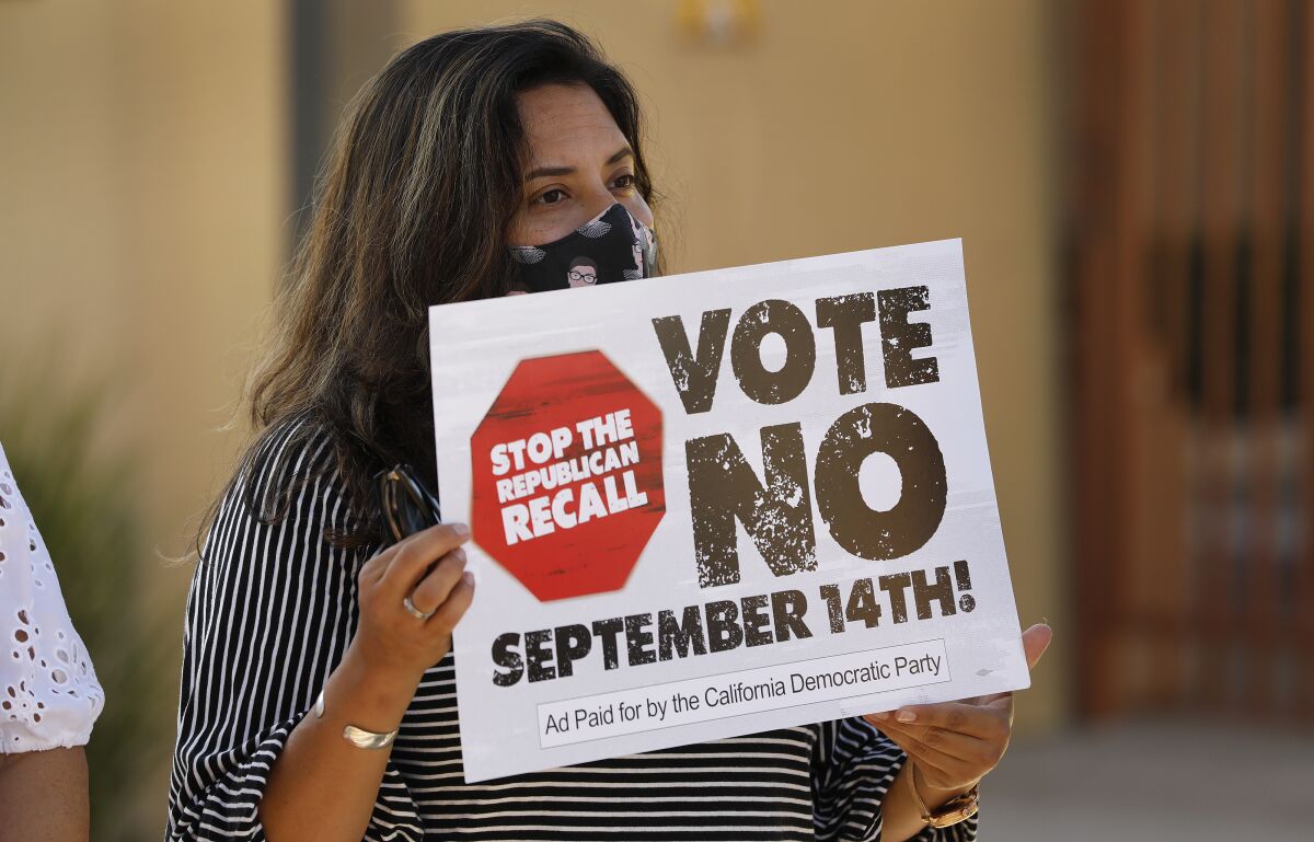 A person holds up a "Vote No" sign.