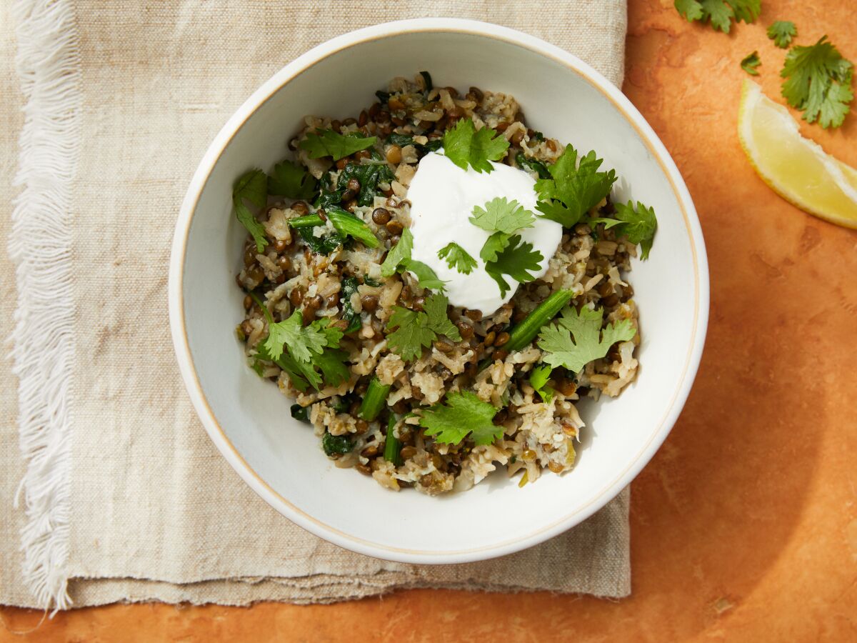 A savory grain bowl topped with grated cauliflower, yogurt and parsley