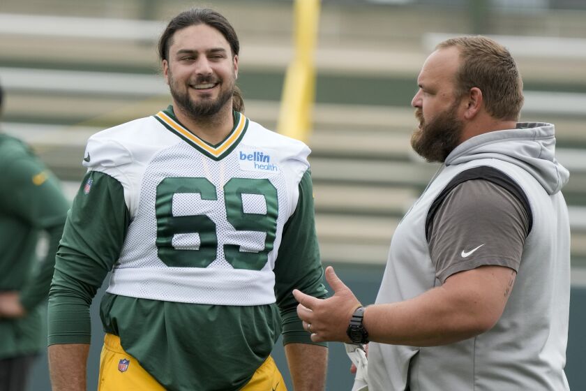 Green Bay Packers' David Bakhtiari talks to coach Luke Butkus during an NFL football OTA practice session Wednesday, May 31, 2023, in Green Bay, Wis. (AP Photo/Morry Gash)