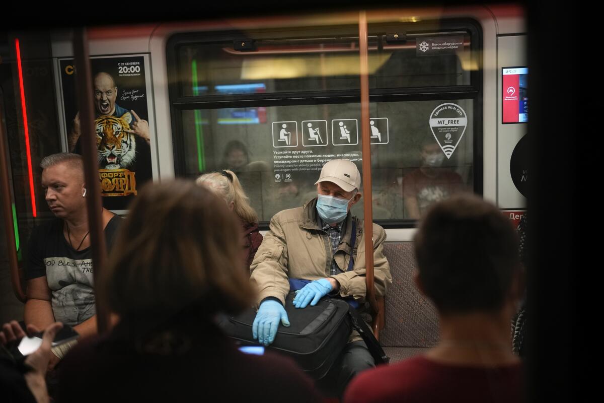 An older man wearing a face mask and gloves to protect against the coronavirus rides a subway car in Moscow.