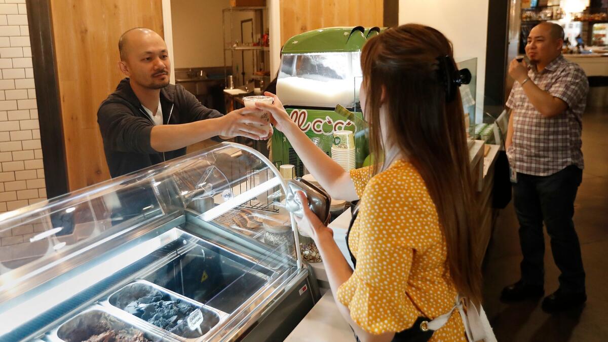 Lakeet Ngov, left, general manager, fills a customer's order at All Coco, located inside Union Market at The District in Tustin.