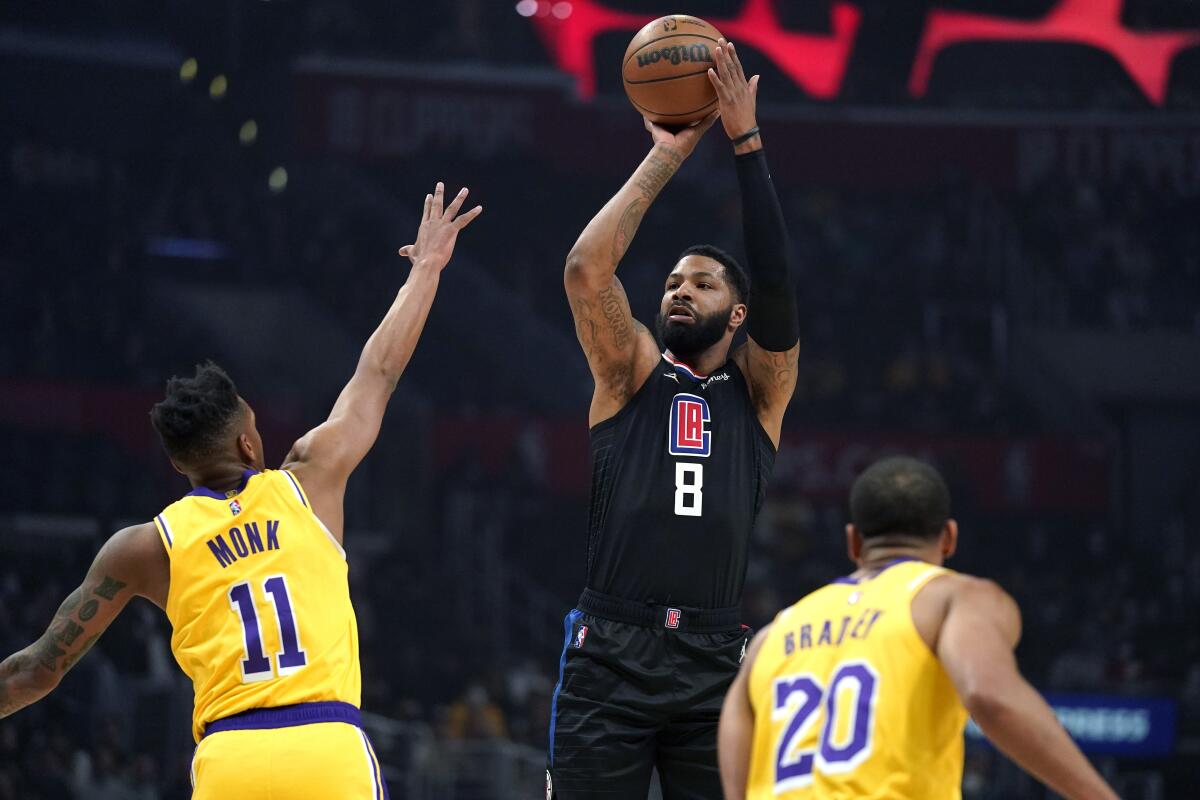 Los Angeles Clippers forward Marcus Morris Sr., center, shoots as Los Angeles Lakers guard Malik Monk, left, and guard Avery Bradley defend during the first half of an NBA basketball game Thursday, Feb. 3, 2022, in Los Angeles. (AP Photo/Mark J. Terrill)