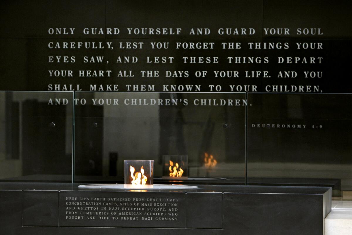 A flame under a black wall engraved with writing.