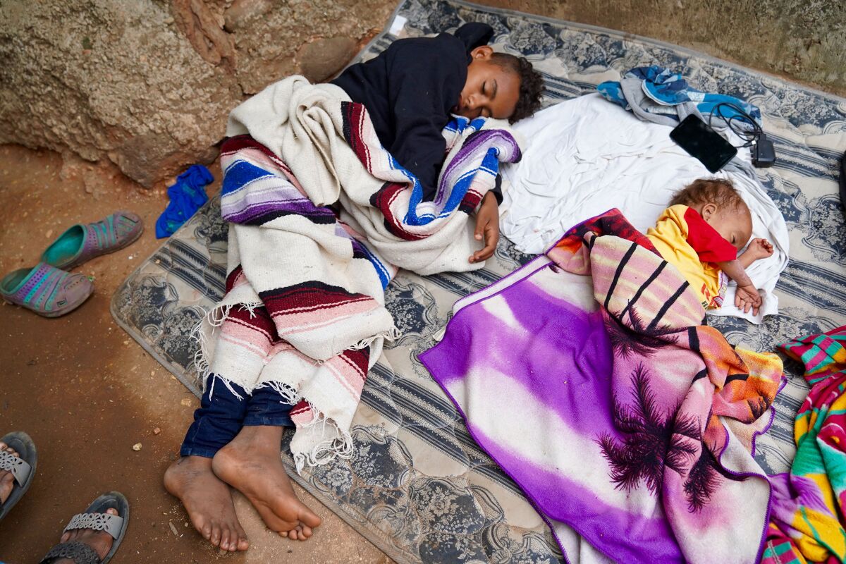 Hondurans Anthony Torres, 13, and his brother, Jose Alejandro, 3, sleep on blankets on the ground