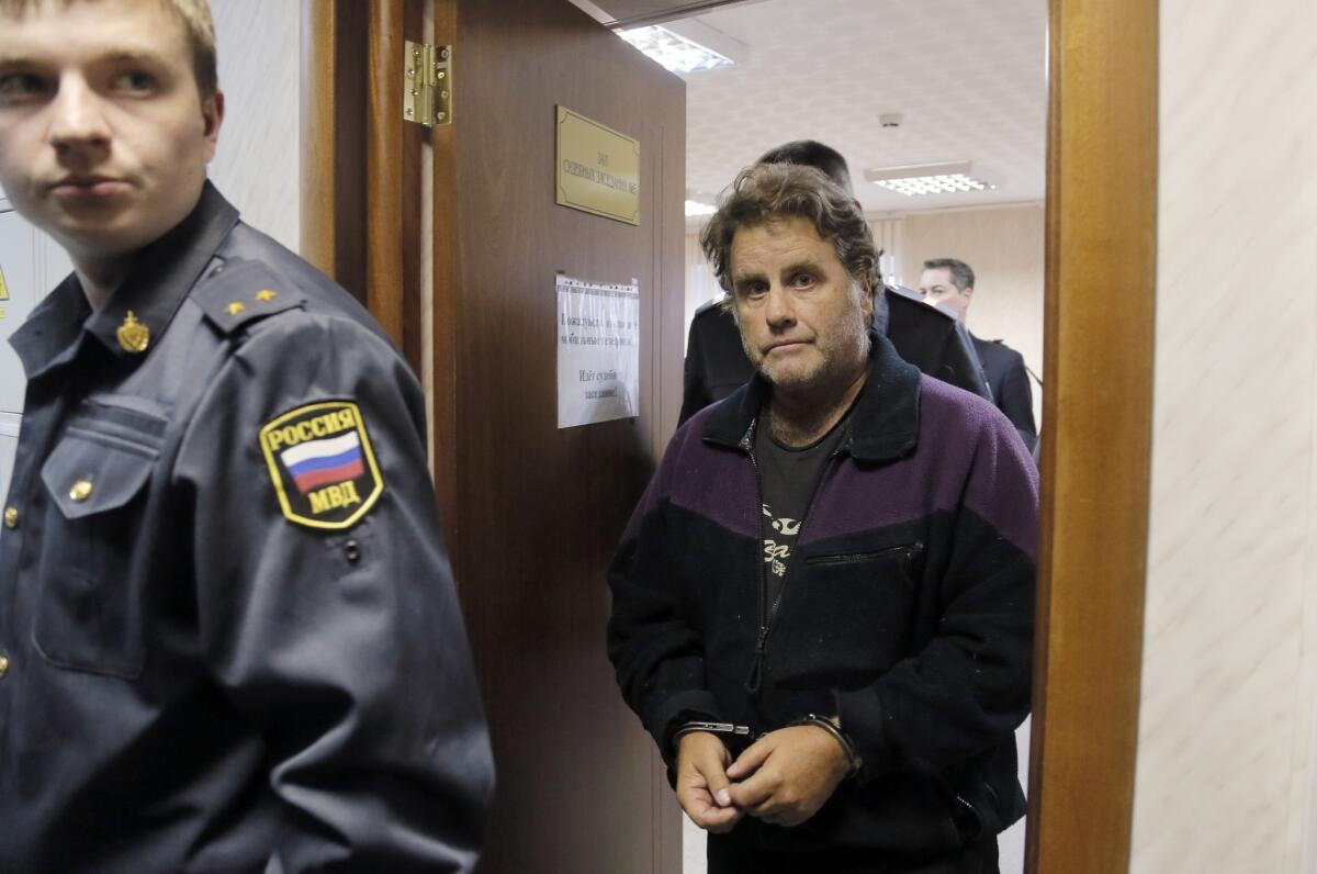 A Russian police officer escorts Greenpeace activist Peter Willcox in court in Murmansk.