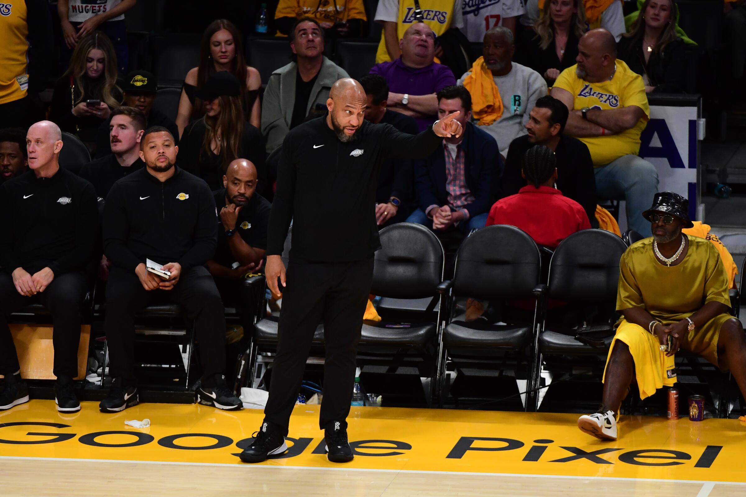 Lakers coach Darvin Ham stands on the sideline and points toward the court 