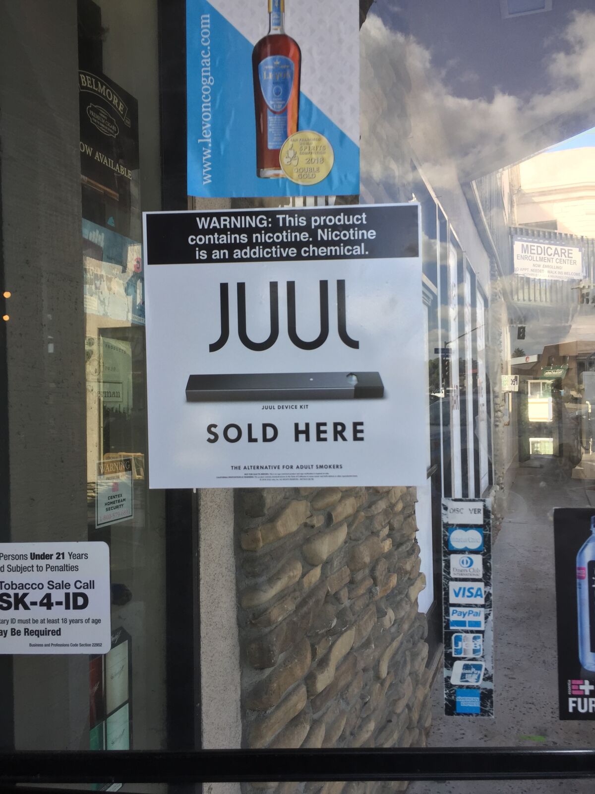 A sign on the Wine Time Deli's front door advertises the availability of a popular brand of e-cigarettes and cartridges.