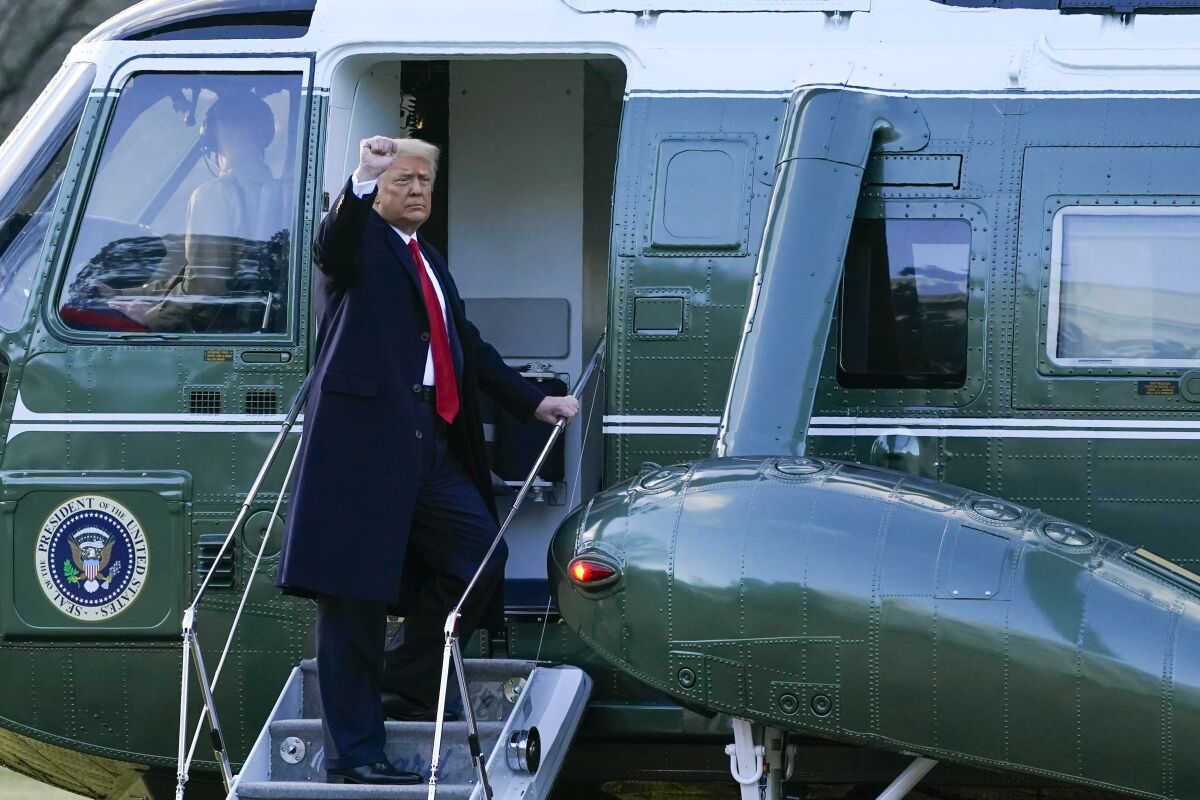 President Trump raises his right fist while standing on the steps to Marine One helicopter