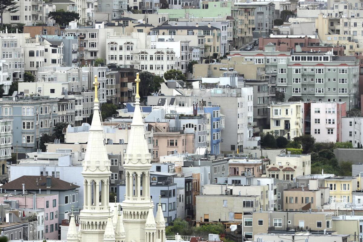 The twin white steeples of Sts. Peter and Paul Church rise amid housing in San Francisco. 