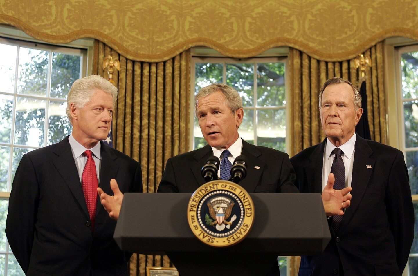 President George W. Bush speaks from the White House after Hurricane Katrina in 2005, as former presidents Bill Clinton, left, and George H.W. Bush look on.