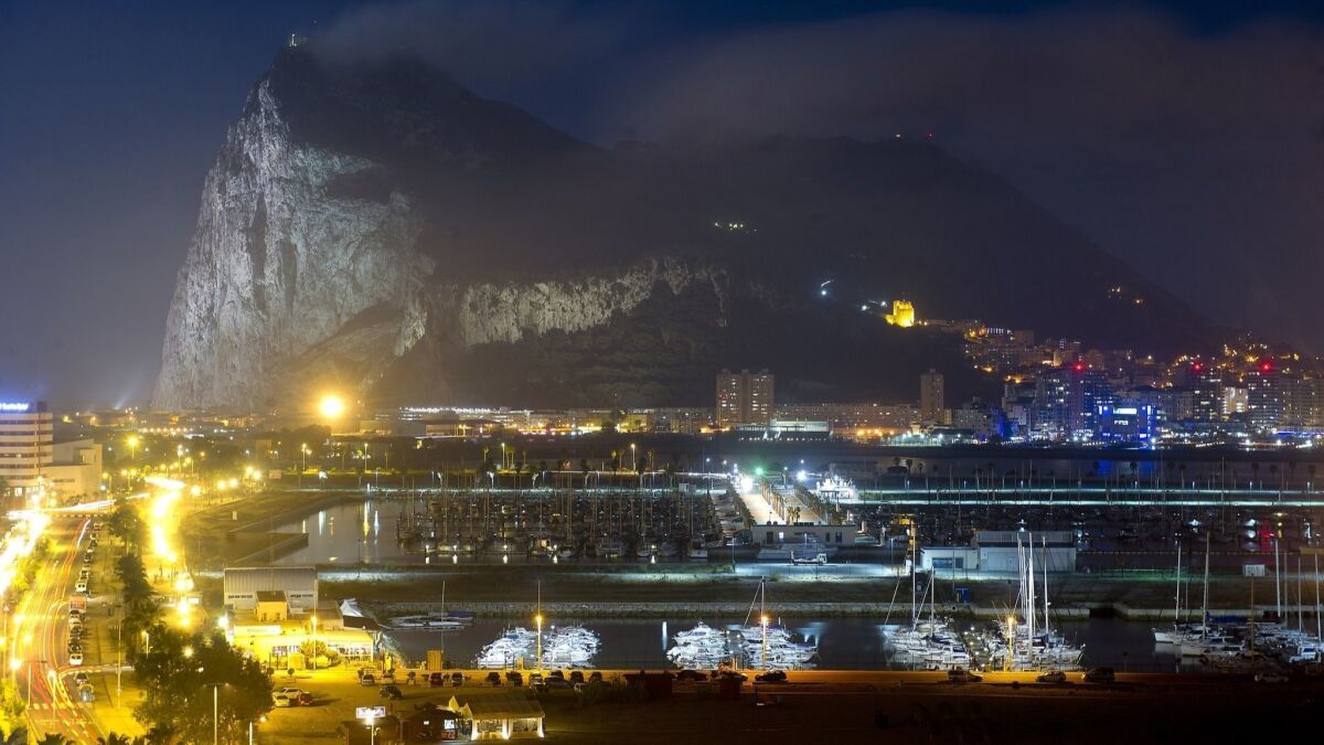 The rock of Gibraltar looms over the adjacent harbor in a night scene.