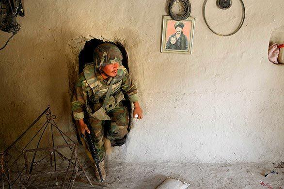 An Afghan soldier searches a home after arriving with U.S. Marines in Main Poshteh, Afghanistan. The Marines are part of an operation to take areas in the Southern Helmand Province, which is a stronghold of Taliban insurgency.