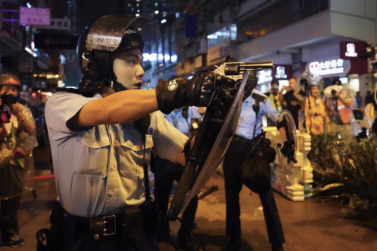 A policeman points a weapon during a protest in Hong Kong, Sunday, Aug. 25, 2019. Hong Kong police have rolled out water cannon trucks for the first time in this summer's pro-democracy protests. The two trucks moved forward with riot officers Sunday evening as they pushed protesters back along a street in the outlying Tsuen Wan district. (AP Photo/Vincent Yu)