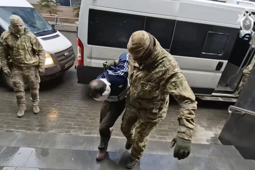 In this photo taken from video released by Investigative Committee of Russia on Sunday, March 24, 2024, a suspect in the Crocus City Hall shooting on Friday is escorted to the Russian Investigative Committee headquarters in Moscow, Russia. (Investigative Committee of Russia via AP)