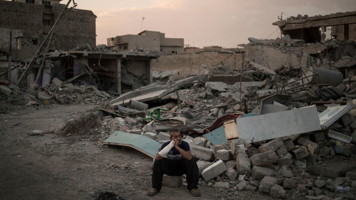 Saddam Salih Ahmed, who was injured when his house was hit by an explosion, sits on his damaged street in Mosul, Iraq on July 13.