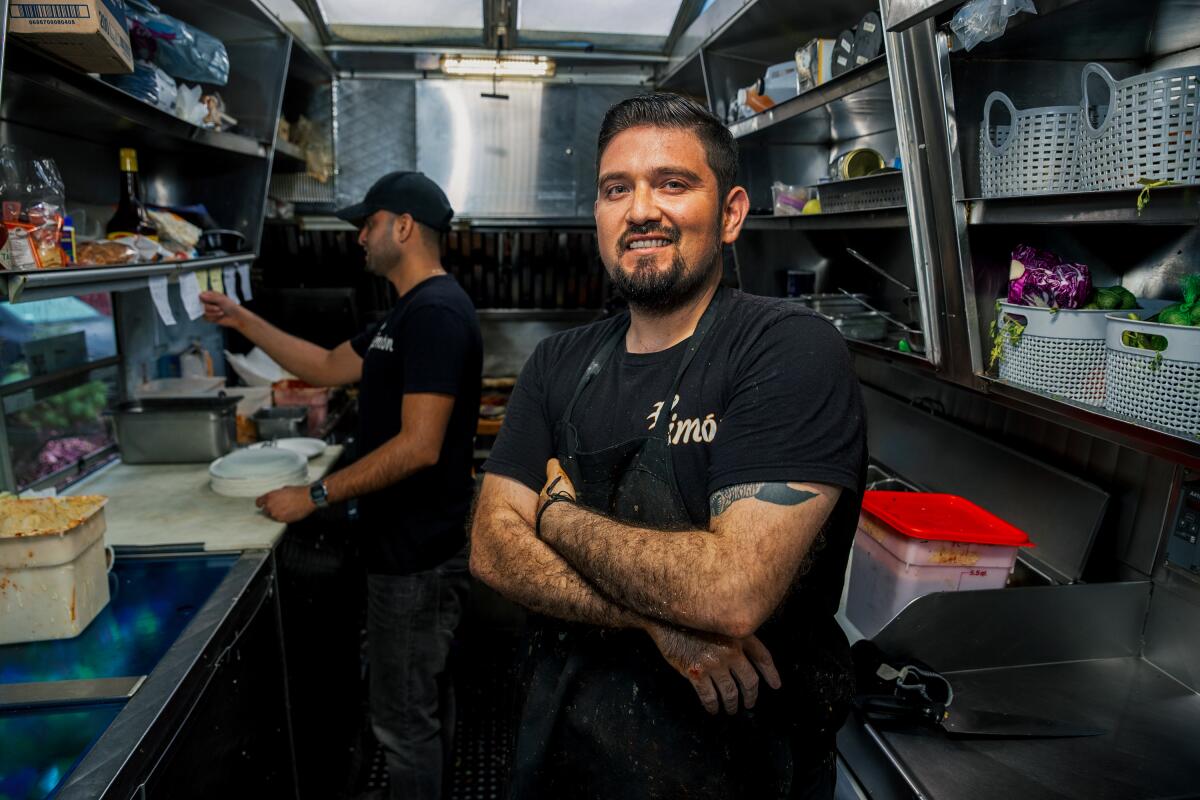 A smiling man with arms crossed inside a food truck kitchen
