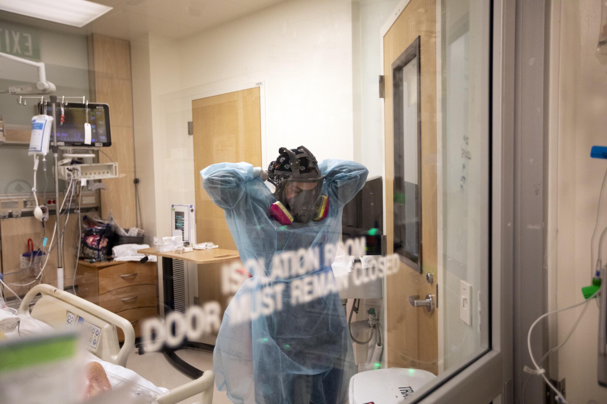 Nurse Armela Masihi removes her gown as she exits a COVID-19 patient's room at Martin Luther King Jr. Community Hospital.