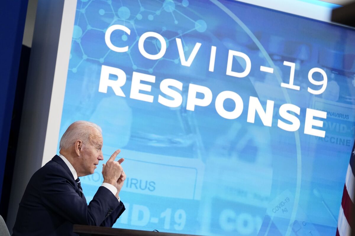 President Biden speaks in front of a blue screen that says "COVID-19 response."