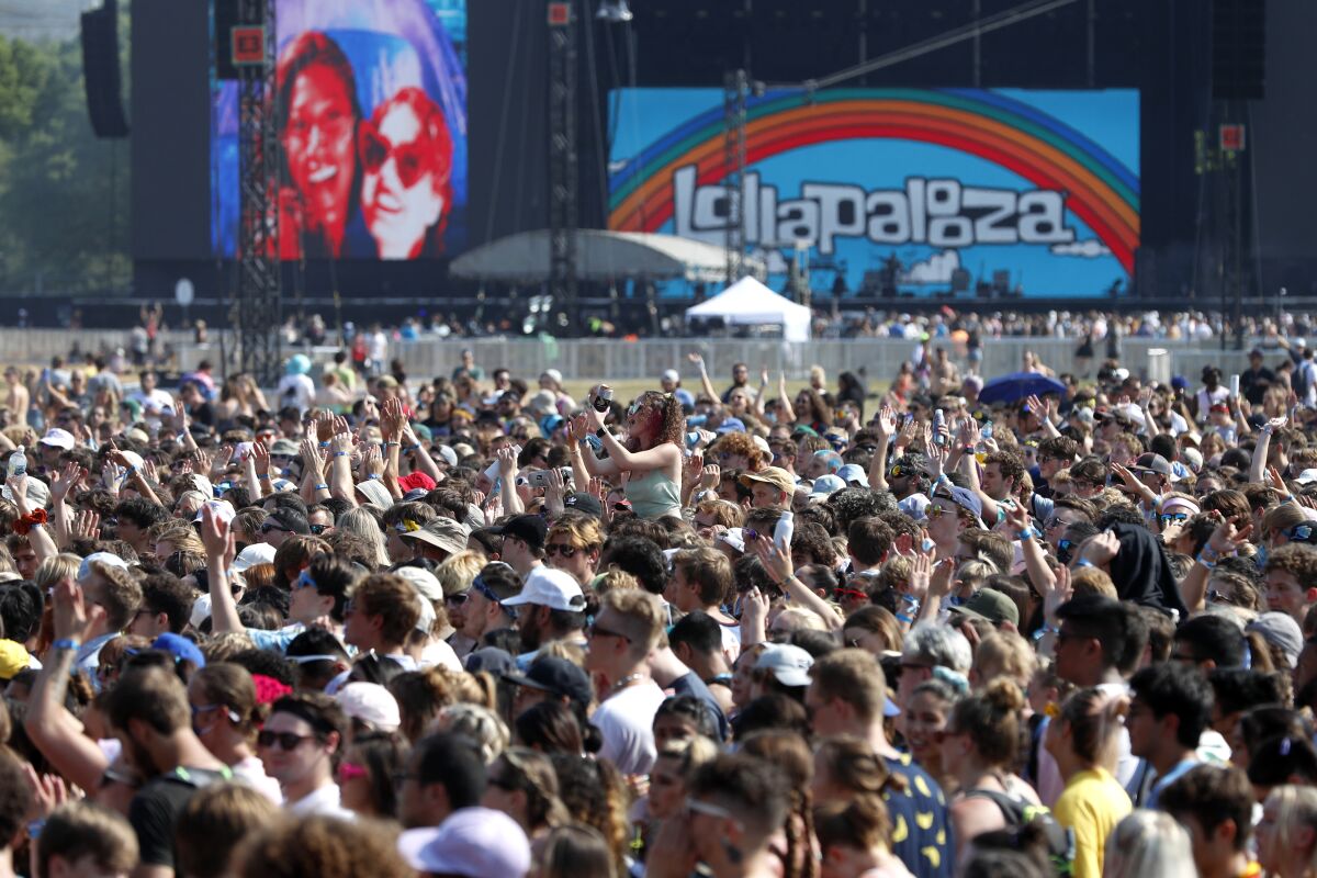 FILE - In this July 29, 2021 file photo, fans gather and cheer on day one of the Lollapalooza music festival at Grant Park in Chicago. Illinois dispensaries sold a record $127.8 million in recreational marijuana in July, with a big boost coming from out-of-state fans who converged on Chicago for the Lollapalooza music festival. (AP Photo/Shafkat Anowar File)