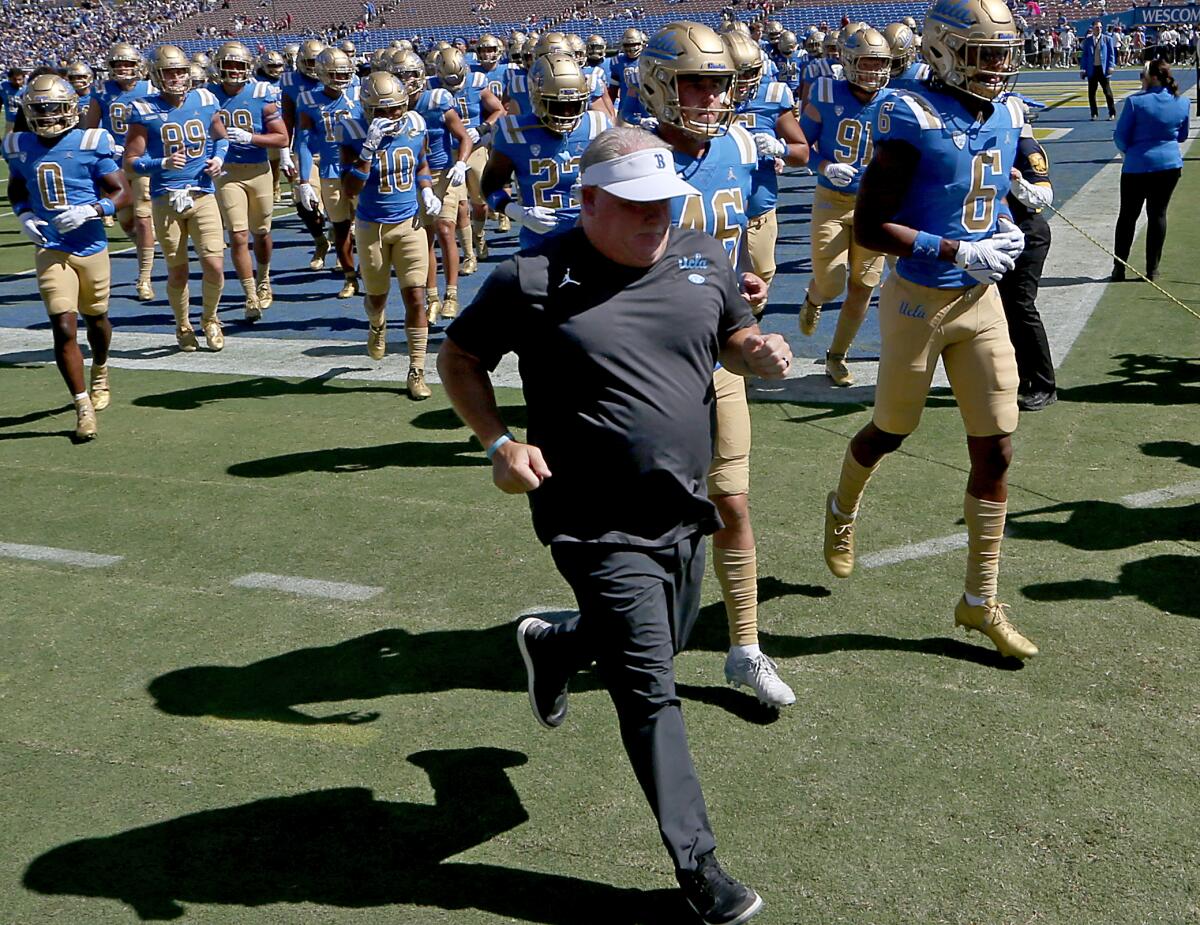 Coach Chip Kelly runs with UCLA players.